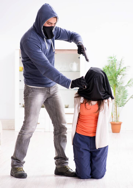 Aseistettu mies pahoinpitelee nuorta naista kotona - Valokuva, kuva