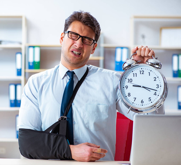 Бизнесмен со сломанной рукой работает в офисе - Фото, изображение