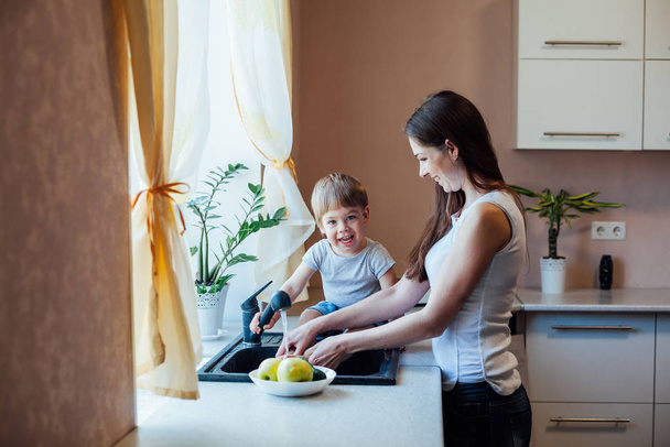 kitchen mom son wash fruits and vegetables - Foto, Bild