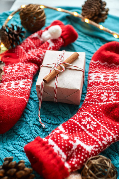 Composición navideña, calcetines rojos con un regalo en un suéter de punto azul con una guirnalda y conos
 - Foto, imagen