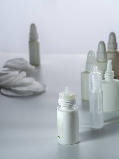 Dropper und Sprays mit verschiedenen Medikamenten für Augen und Nase sowie Baumwollkissen befinden sich auf einem senkrechten Hintergrund. - Foto, Bild