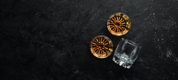 Whiskey in glasses on black stone table. Top view. Free space for your text. - Photo, image