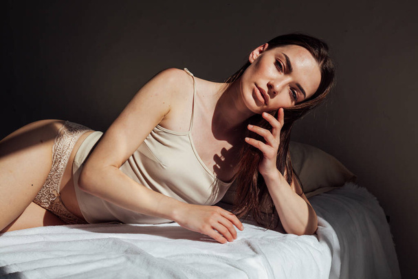 brunette nainen harmaa alusvaatteet sijaitsee sängyllä makuuhuoneessa
 - Valokuva, kuva