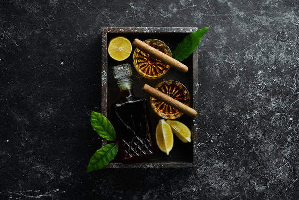 Whisky in Gläsern und kubanische Zigarren auf einem Tisch aus schwarzem Stein. Ansicht von oben. Freiraum für Ihren Text. - Foto, Bild