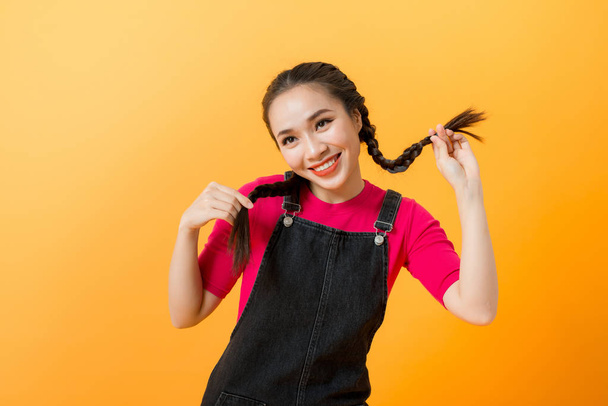Cute mischievous young asian woman pulling her pigtails - Photo, Image