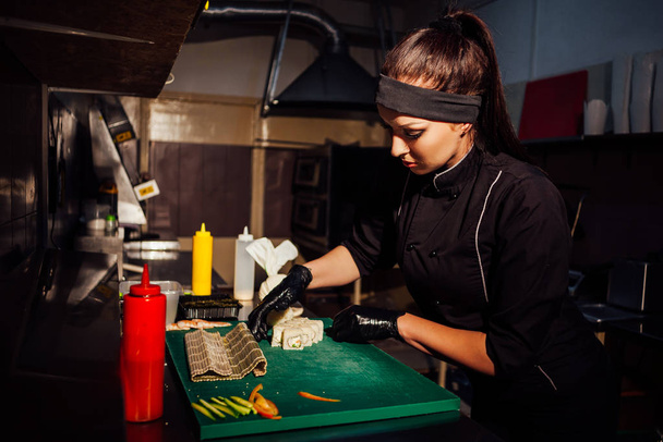 Женщина шеф-повар iprepares суши ресторан на кухне
 - Фото, изображение