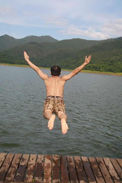 muž Asie skok do vody v jezeře s pozadím mountain view - Fotografie, Obrázek