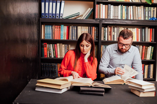 a man and a woman reading a book in the library before the exam - Fotoğraf, Görsel