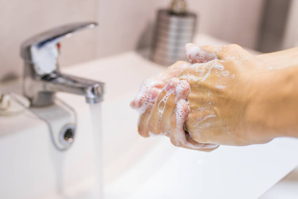 χέρια στο νιπτήρα πλύσιμο με νερό βρύσης και σαπούνι - Φωτογραφία, εικόνα