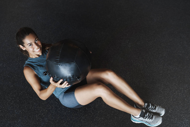 Upper-angle shot motivated happy and active gorgeous sportswoman in activewear, lie on gym floor, perform fitness exercises, crunching abdominal abs and move heavy medicine ball sideways smiling - Zdjęcie, obraz