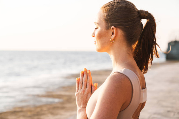 Fitness woman meditate outdoors on beach. - Zdjęcie, obraz