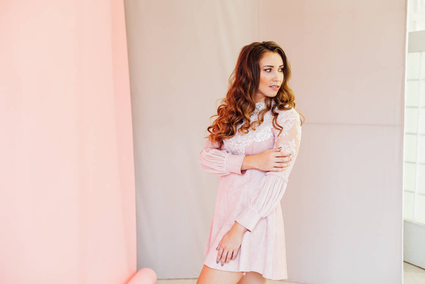 Portré egy gyönyörű divatos nő haj fürtök rózsaszín ruhában - Fotó, kép