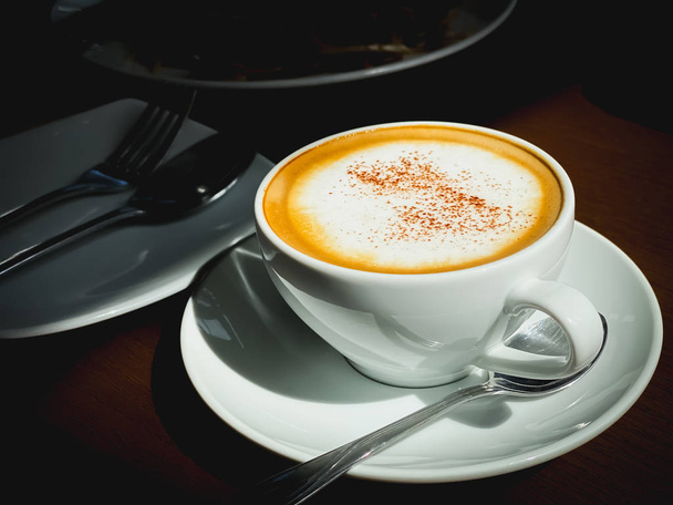 Закрыть белую чашку горячего кофе капучино в темной сцене еды и выпить закутки - Фото, изображение