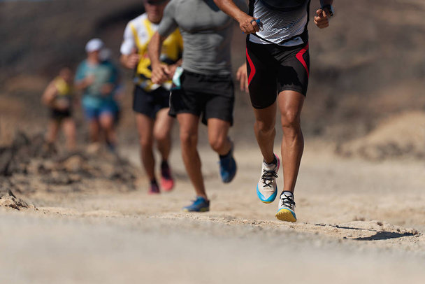 Бегуны бегают по тропе. Ультра бегущие спортсмены ноги закрываются на беговой дорожке - Фото, изображение