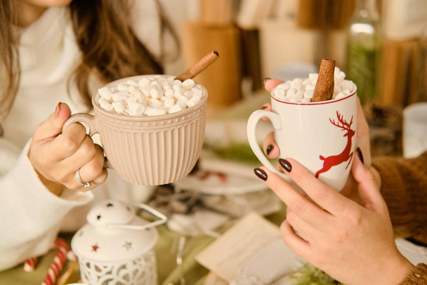 Bekers met warme chocolademelk en marshmallows in vrouwelijke handen. - Foto, afbeelding