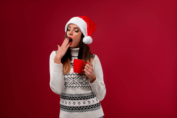 Close up portrait beautifiul caucasian woman in red Santa hat on red studio background. Christmas and New Year holiday concept. - Фото, изображение
