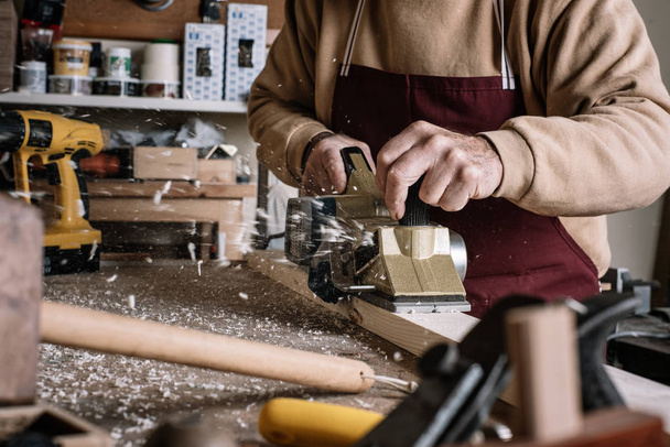 Carpinteiro trabalhando a madeira com uma escova elétrica
 - Foto, Imagem