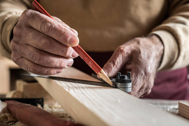 Carpenter measuring a plank with a red pencil and a metal ruler - Foto, Bild