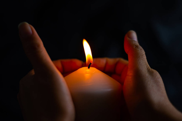 Hand protecting candle light from the wind in darkness - Zdjęcie, obraz
