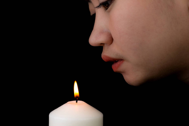 Giovane donna che soffia una candela su sfondo nero
 - Foto, immagini