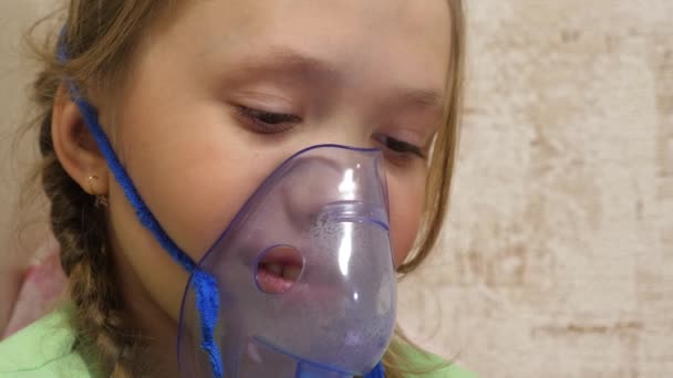kind met tablet is ziek en ademt via een inhalator. close-up. klein meisje behandeld met een inhalatiemasker op haar gezicht in het ziekenhuis. Peuter behandelt griep door inhalatiedamp in te ademen. - Video