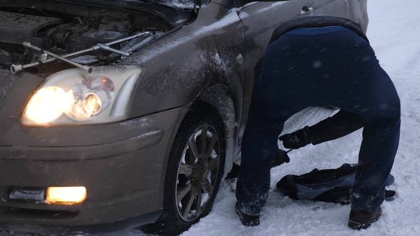 man raises car jack. car broke down on a snowy road. - Photo, Image