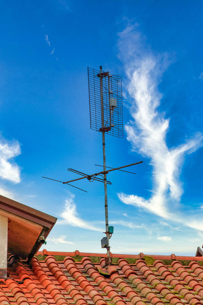 tv antenna tetején egy narancssárga tető ellen kék ég - Fotó, kép