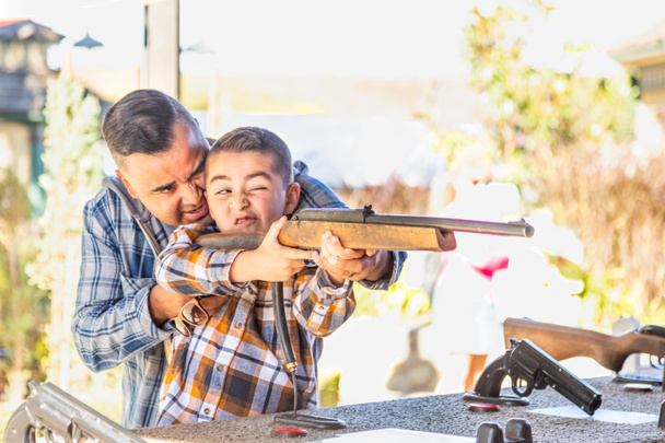 Raza mixta Padre e hijo en el campo de tiro del recinto ferial
 - Foto, Imagen
