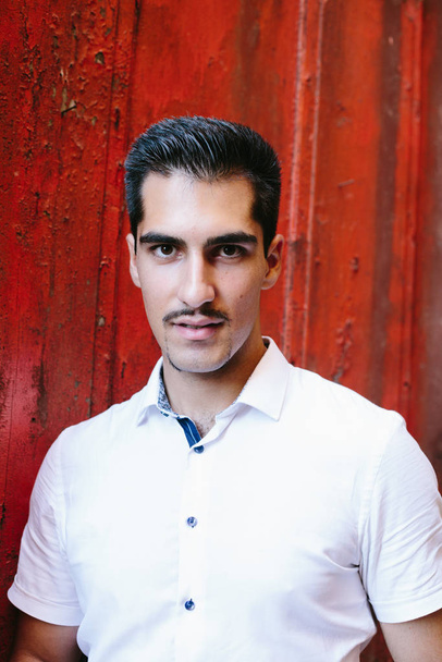 Portrait Of Young Handsome Man wearing moustache Outdoor on red wall background - Fotoğraf, Görsel