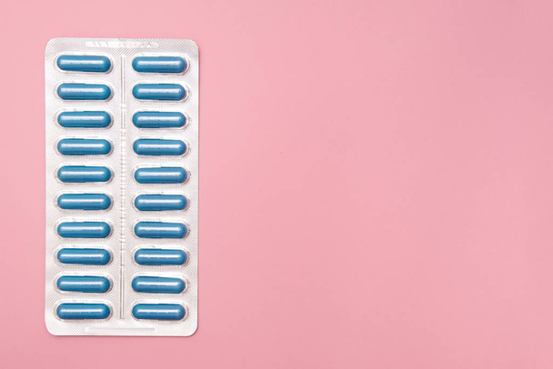 Antibiotica en antimicrobiële pillen voor de behandeling van seksueel overdraagbare ziekten Std, blauwe capsules in blister op roze achtergrond, kopieerruimte - Foto, afbeelding