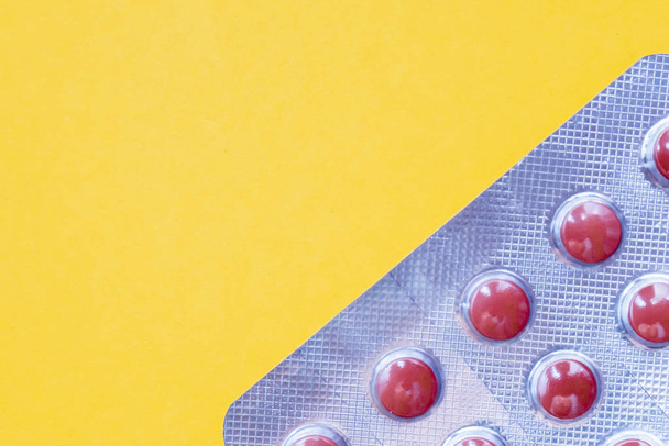 A blister pack ob brown tablets on yellow background, copy space - Φωτογραφία, εικόνα