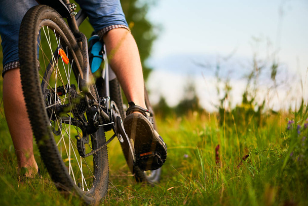 Πόδια ενός αρσενικού ποδηλάτη και ποδήλατο βουνού κοντά - Φωτογραφία, εικόνα