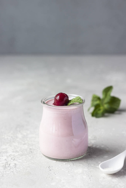 Delicious Italian dessert cherry panna cotta with fresh cherries and mint in jars. Light grey stone background, selective focus. Copy space. - 写真・画像