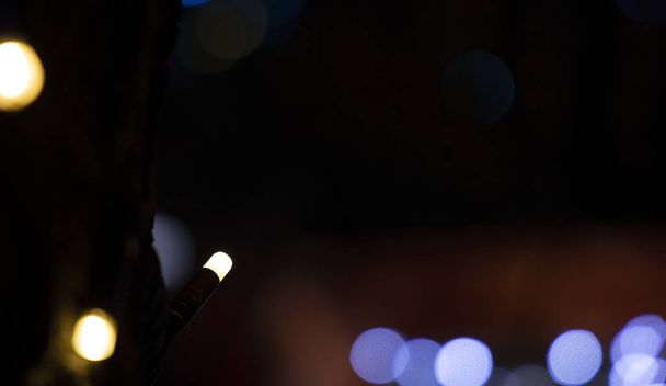 γιρλάντα Χριστουγεννιάτικα φώτα φωτισμός διακοσμητική λάμπα προσκήνιο και bokeh φωτισμού μη εστιασμένη έννοια φόντο κενό χώρο αντίγραφο για το κείμενό σας  - Φωτογραφία, εικόνα