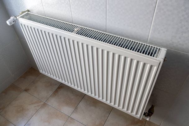 Radiador de calefacción de metal blanco montado en una pared en el interior de la habitación
. - Foto, imagen