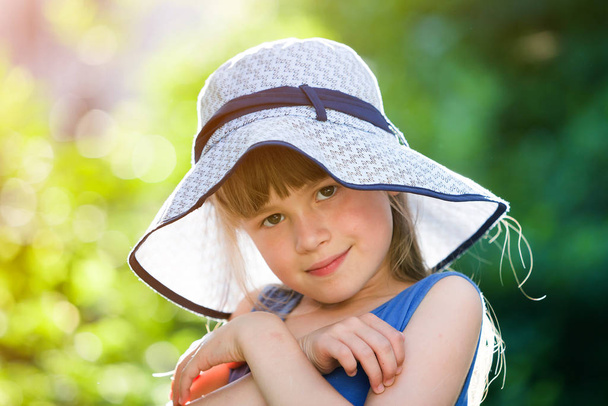 Close-up portrait of happy smiling little girl in a big hat. Chi - 写真・画像