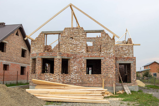 Unfinished brick house with wooden roof structure under construc - Foto, afbeelding