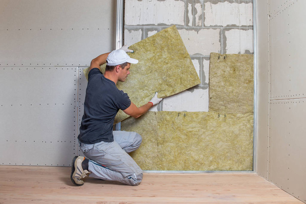 Worker insulating a room wall with mineral rock wool thermal ins - 写真・画像