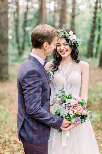 Bride and groom in forest kissing. newlyweds bride and groom at a wedding in nature, green forest, are kissing and smiling. Rustic Wedding Couple - Photo, Image