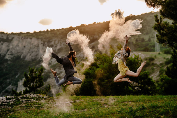 Young beautiful barefoot couple dancer practicing modern dance at mountain field - Valokuva, kuva