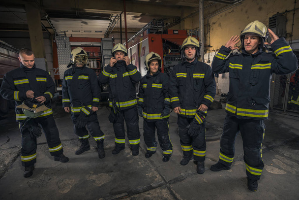 Portrait of firefighters standing by a fire engine. - Photo, Image