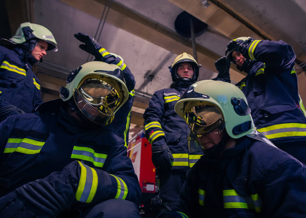 Retrato del grupo de bomberos con uniforme protector dentro de la estación de bomberos - Foto, imagen