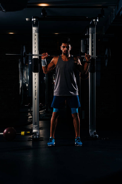 Chudy muskularny mężczyzna ćwiczący z ciężarkami na siłowni - Zdjęcie, obraz