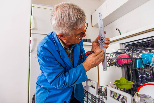 Mayores fontanero reparar los electrodomésticos en la cocina
 - Foto, Imagen
