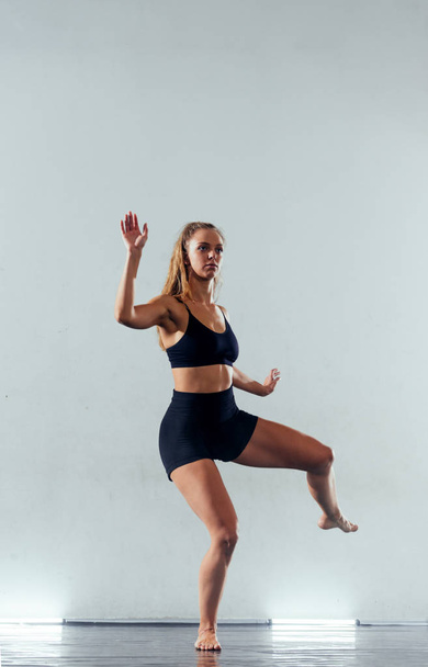 Slim młoda kobieta w rajstopach praktykujących nowoczesny styl baletu stanowi - Zdjęcie, obraz