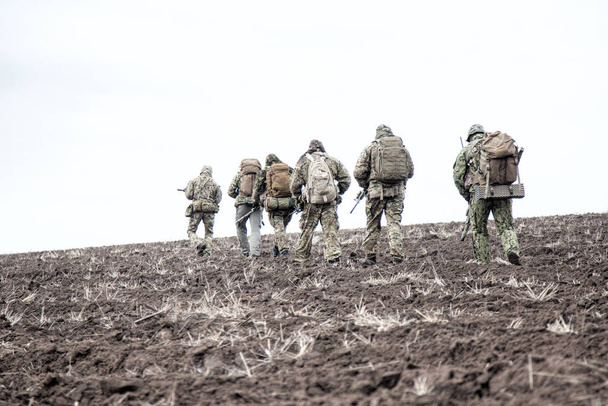 Gruppo di soldati dell'esercito in marcia in campo fangoso
 - Foto, immagini