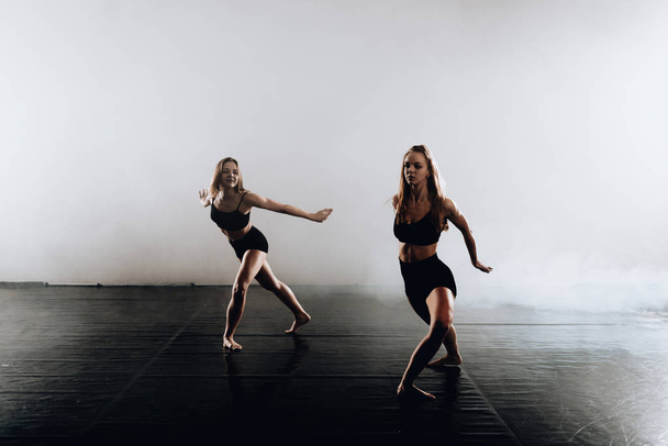 Pareja de mujeres flexibles realizando un movimiento de danza artística
 - Foto, Imagen