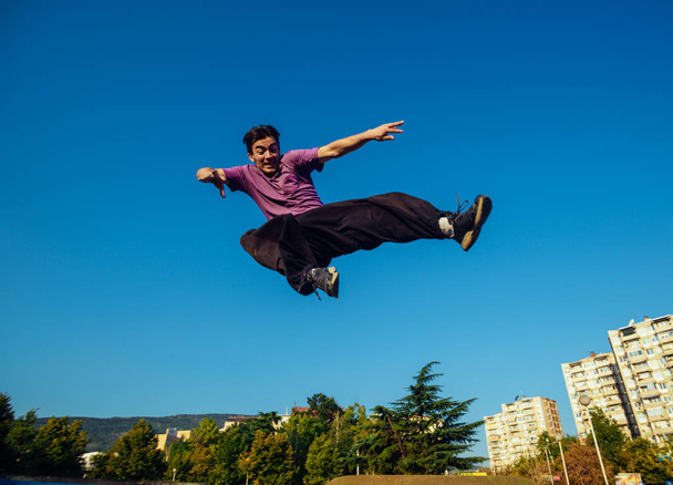 Uomo muscolare a mezz'aria durante l'esecuzione di un calcio laterale volante allo skate park
 - Foto, immagini