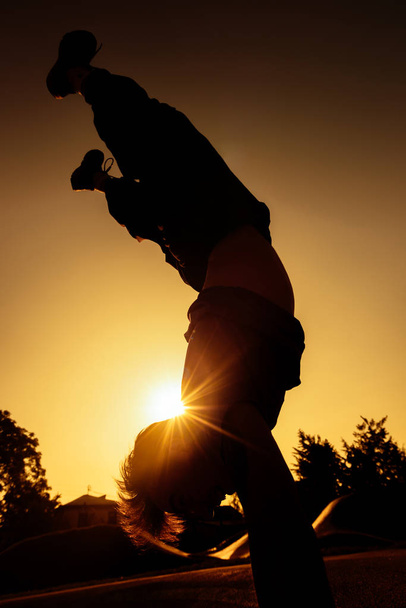 Atletische kerel tijdens een handstand oefening in een stad skatepark - Foto, afbeelding