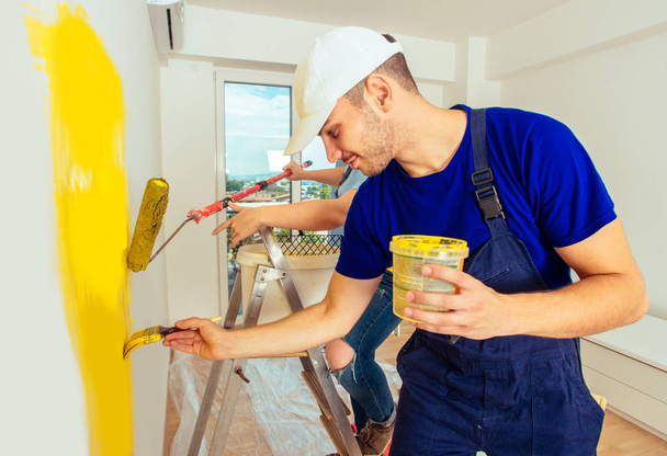 Cheerful married couple renovate living room while painting it w - Foto, imagen